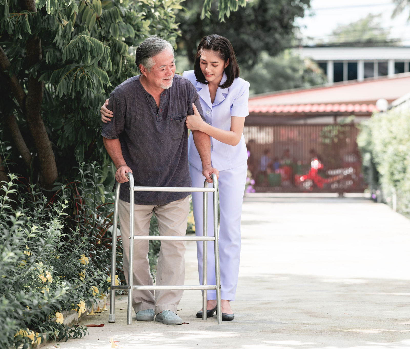 Caregiver warmly supporting an older gentleman outdoors